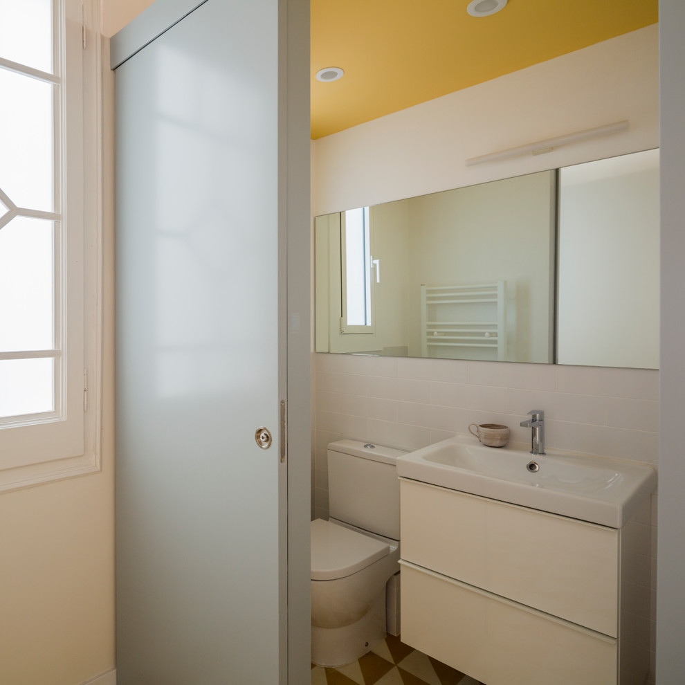 Modelo de aseo contemporáneo pequeño con armarios con paneles lisos, puertas de armario blancas, sanitario de dos piezas, paredes blancas y lavabo integrado