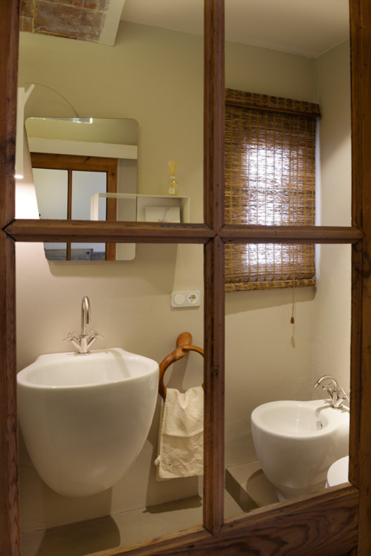 Immagine di un bagno di servizio minimalista di medie dimensioni con bidè, pareti beige e lavabo sospeso