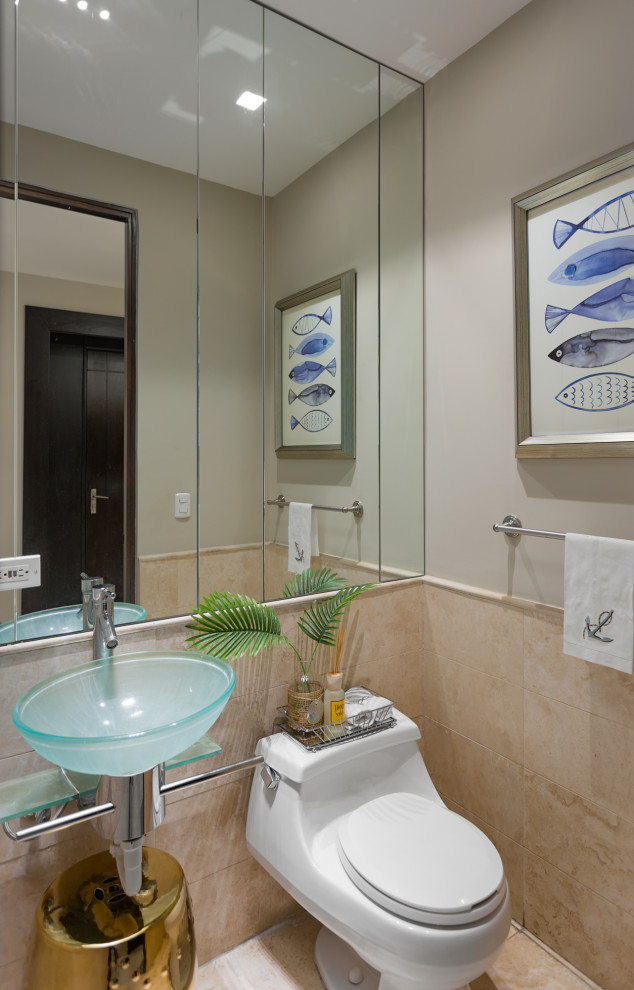 Modern inredning av ett litet turkos turkost toalett, med öppna hyllor, turkosa skåp, en toalettstol med hel cisternkåpa, beige kakel, marmorkakel, beige väggar, marmorgolv, ett fristående handfat, bänkskiva i glas och beiget golv