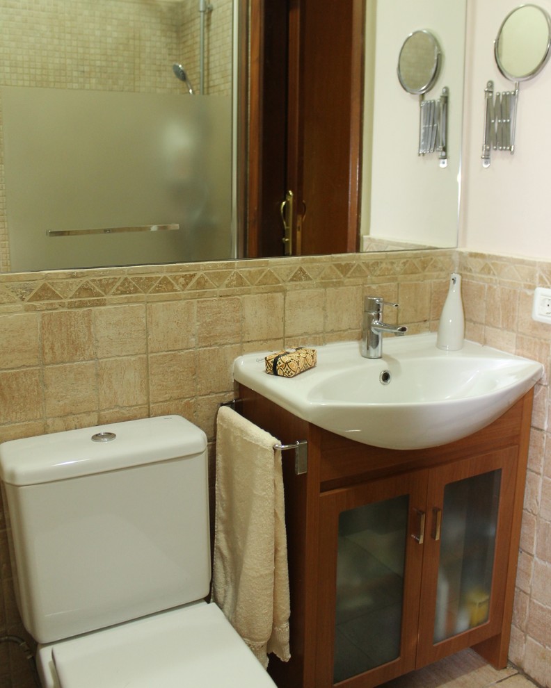 Example of a small mountain style powder room design in Other with glass-front cabinets, medium tone wood cabinets, a two-piece toilet, beige walls and a drop-in sink