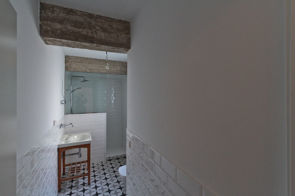 Photo of a small industrial cloakroom in Madrid with a one-piece toilet, ceramic tiles, white walls, porcelain flooring and an integrated sink.