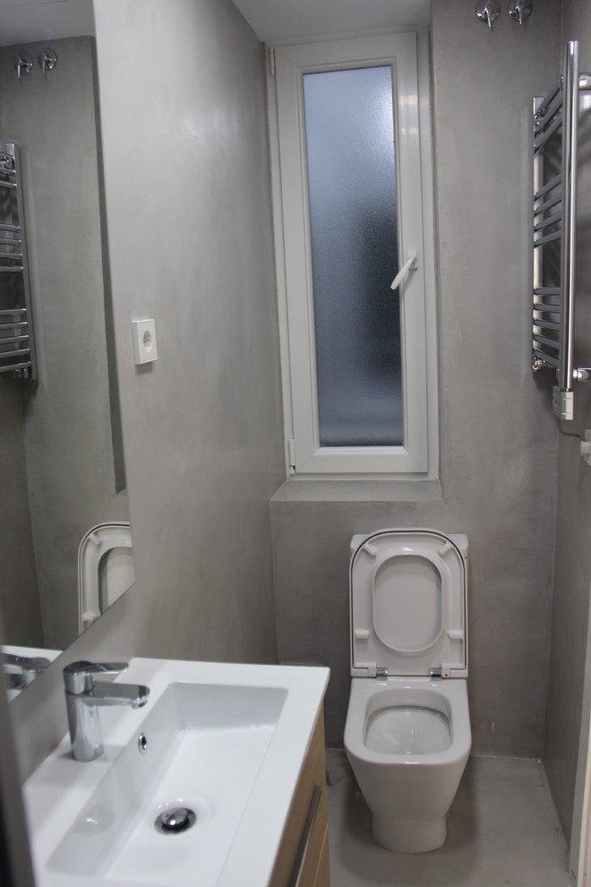 Cette photo montre un petit WC et toilettes industriel avec un placard à porte plane, WC séparés, un mur gris et un lavabo intégré.