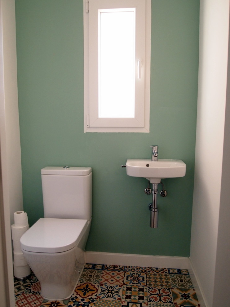 Пример оригинального дизайна: маленький туалет в современном стиле с унитазом-моноблоком, зелеными стенами, полом из керамической плитки, подвесной раковиной и разноцветным полом для на участке и в саду