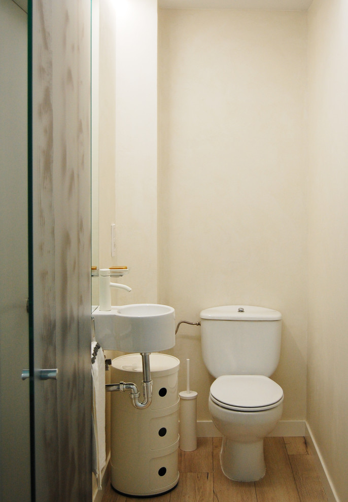 Ispirazione per un piccolo bagno di servizio scandinavo con WC a due pezzi, pavimento in legno massello medio e lavabo sospeso