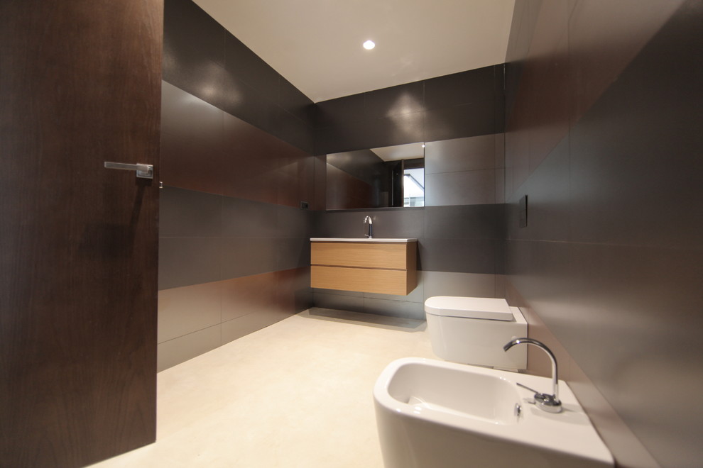 Cette image montre un WC et toilettes design en bois brun de taille moyenne avec un placard à porte plane, un bidet, un mur marron et un lavabo intégré.