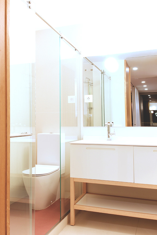 Cette photo montre un WC et toilettes scandinave de taille moyenne avec un placard à porte plane, des portes de placard blanches, WC séparés, un mur blanc, un sol en carrelage de céramique et un lavabo intégré.