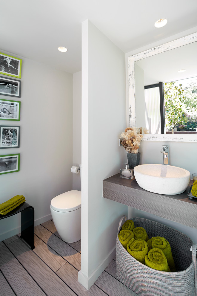 Idee per un bagno di servizio contemporaneo di medie dimensioni con WC monopezzo, pareti bianche, parquet chiaro, lavabo a bacinella, top in legno e top marrone