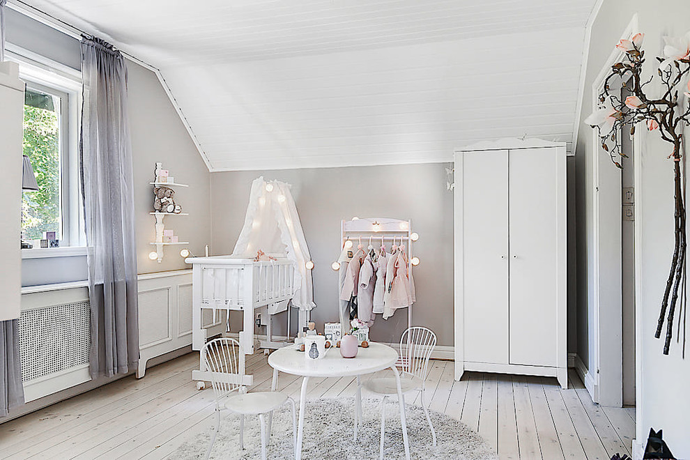 Immagine di una cameretta per neonata scandinava con pareti grigie e pavimento in legno verniciato