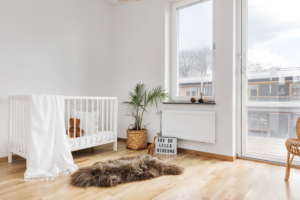Inspiration för ett mellanstort nordiskt babyrum, med vita väggar och ljust trägolv