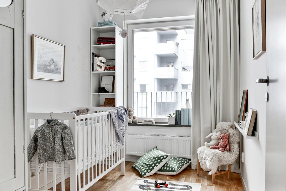 Источник вдохновения для домашнего уюта: нейтральная комната для малыша среднего размера в скандинавском стиле с белыми стенами и паркетным полом среднего тона