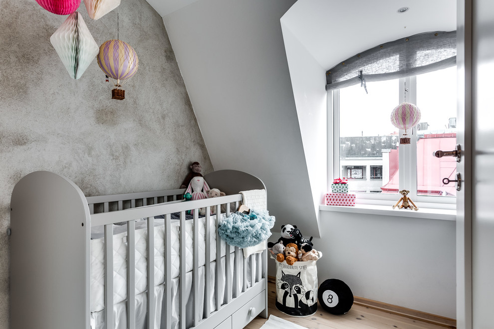 Kleines Skandinavisches Babyzimmer mit weißer Wandfarbe und hellem Holzboden in Stockholm