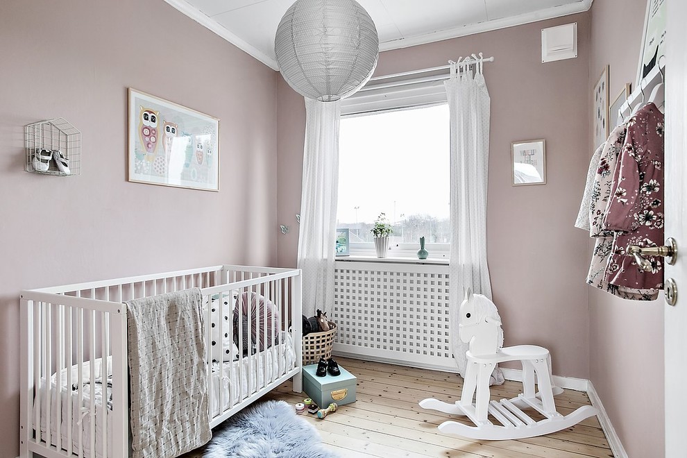 Idee per una cameretta per neonata scandinava con pareti rosa, parquet chiaro e pavimento beige