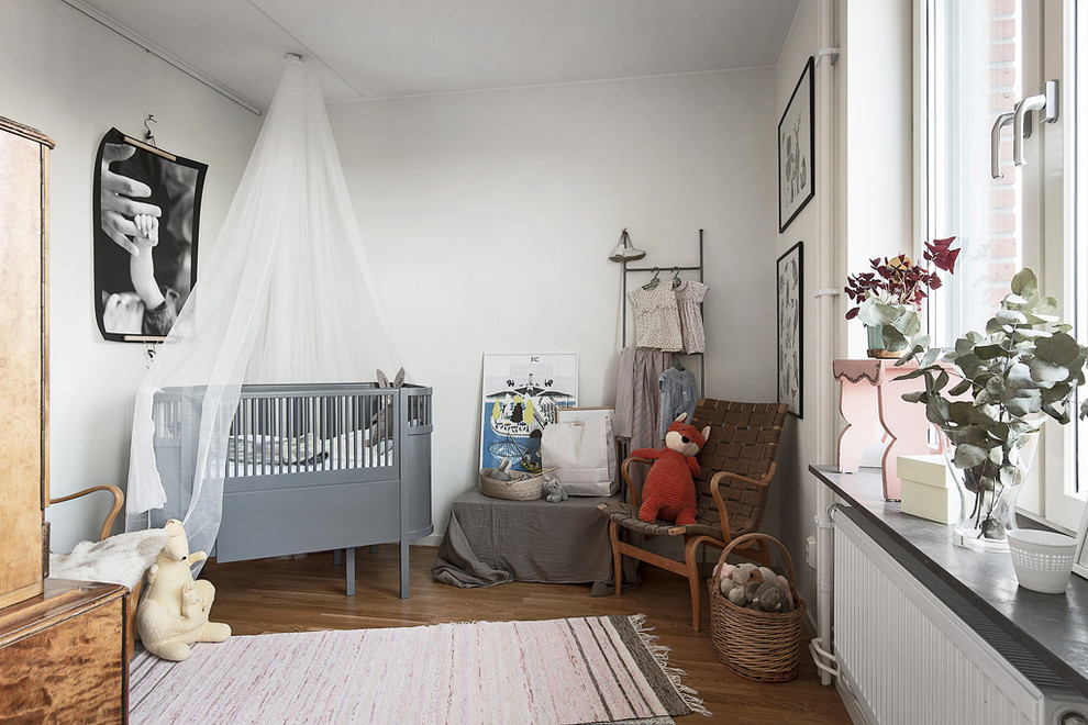 Imagen de habitación de bebé niño nórdica de tamaño medio con paredes blancas, suelo de madera oscura y suelo marrón