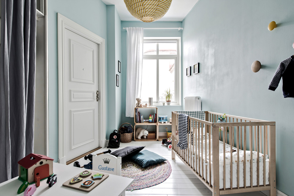Medium sized scandi nursery for boys in Gothenburg with blue walls, painted wood flooring and white floors.