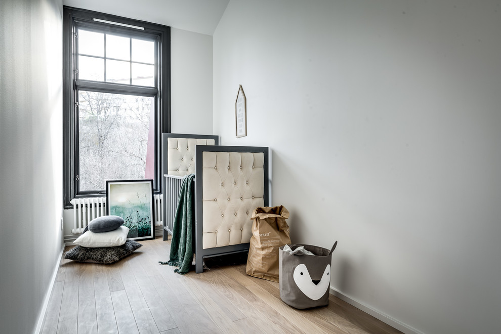На фото: нейтральная комната для малыша среднего размера в скандинавском стиле с серыми стенами, светлым паркетным полом и бежевым полом с