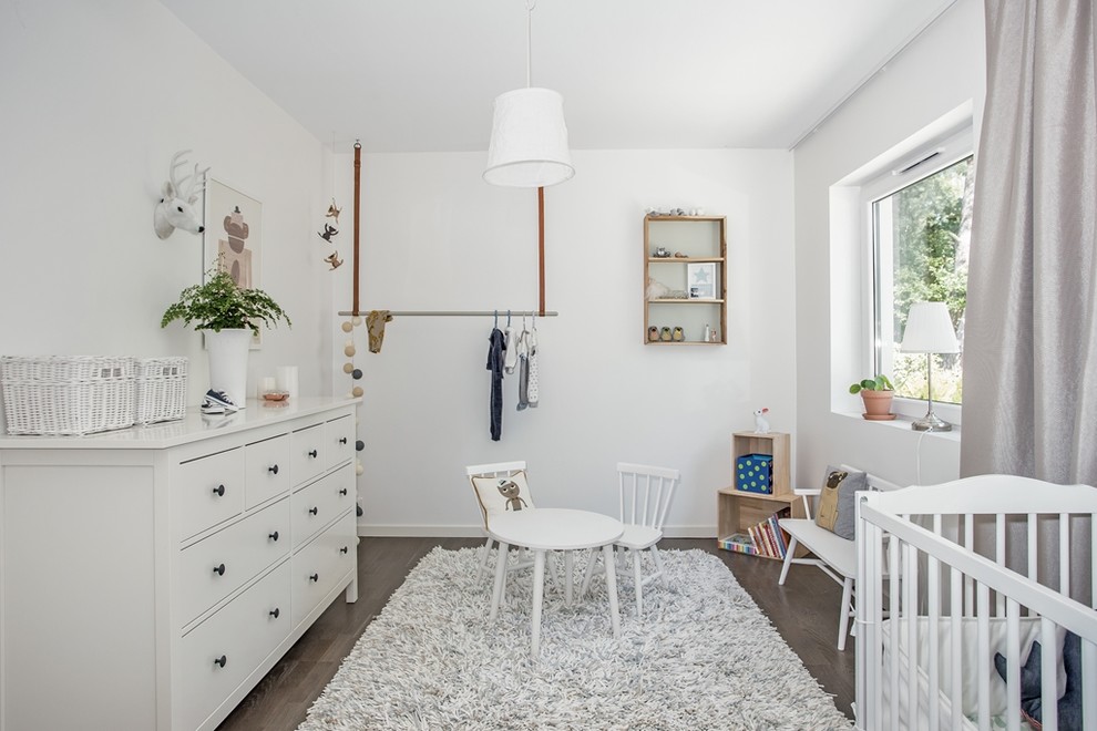 Medium sized scandinavian gender neutral nursery in Stockholm with white walls, dark hardwood flooring and grey floors.
