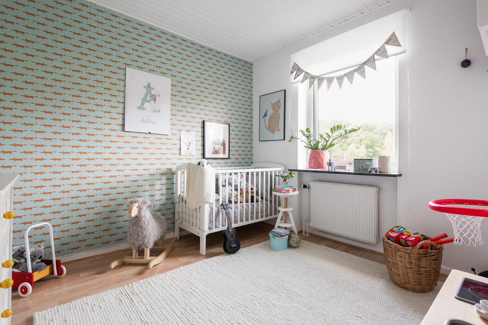 Cette photo montre une chambre de bébé neutre scandinave de taille moyenne avec un mur multicolore, un sol en bois brun et un sol marron.