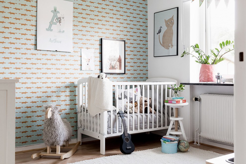 Ispirazione per una cameretta per neonato nordica di medie dimensioni con pareti multicolore e pavimento in legno massello medio