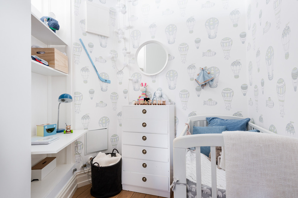 Aménagement d'une petite chambre de bébé garçon scandinave avec un mur blanc et un sol en bois brun.
