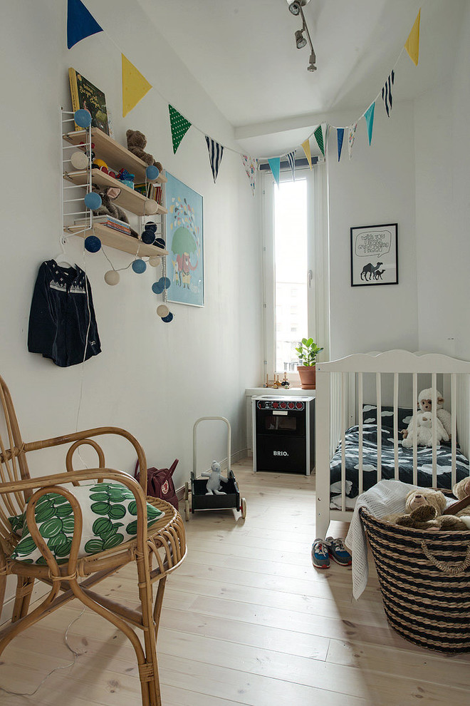 Bild på ett mellanstort minimalistiskt könsneutralt babyrum, med vita väggar, ljust trägolv och beiget golv