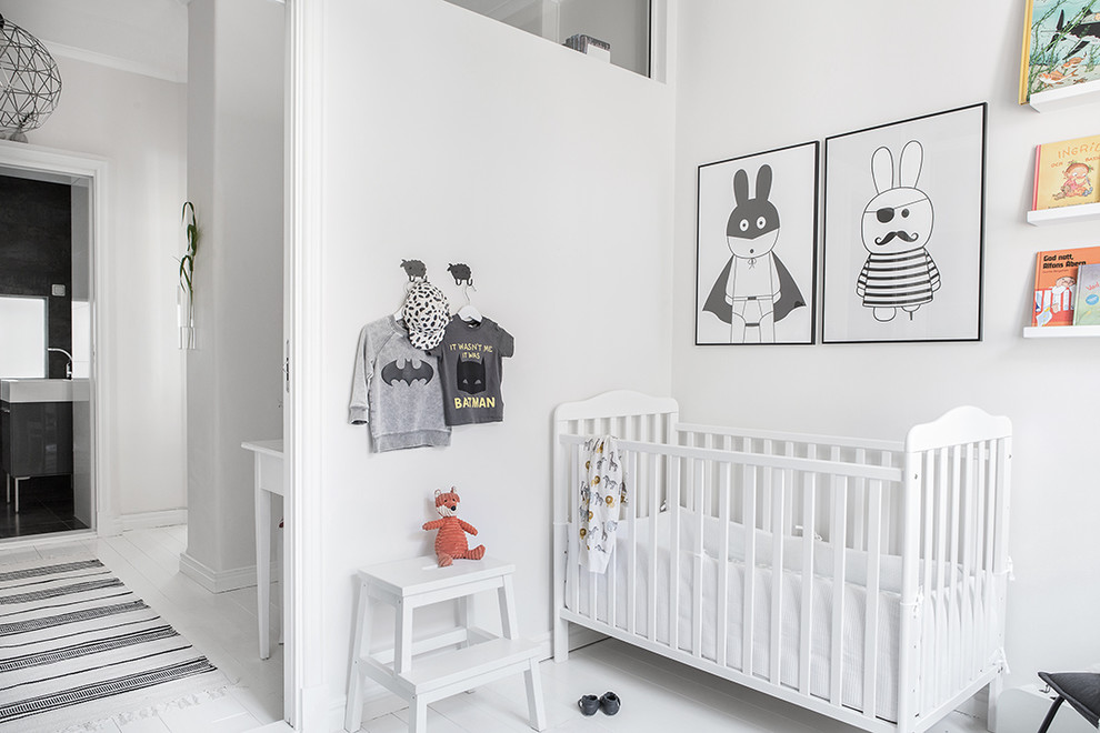 На фото: нейтральная комната для малыша среднего размера в скандинавском стиле с белыми стенами, деревянным полом и белым полом с