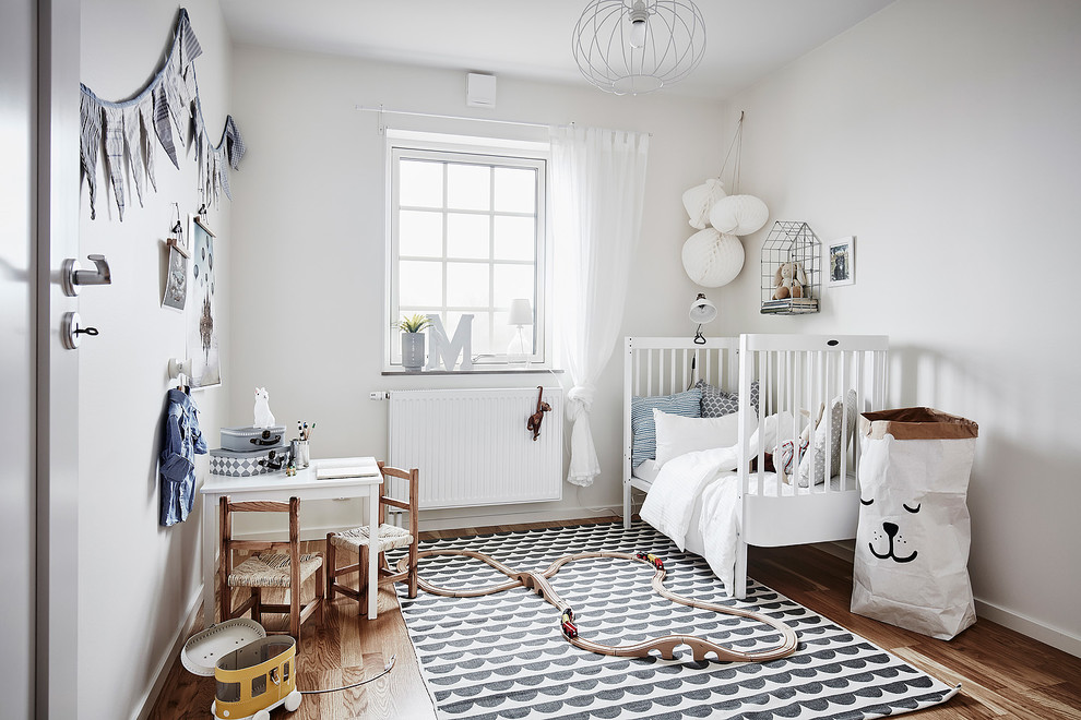 ヨーテボリにあるお手頃価格の中くらいな北欧スタイルのおしゃれな赤ちゃん部屋 (白い壁、淡色無垢フローリング、男女兼用) の写真