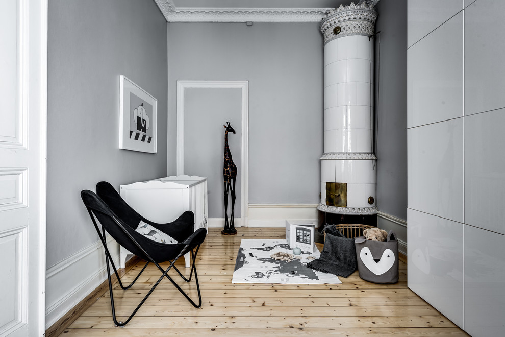 Mittelgroßes, Neutrales Skandinavisches Babyzimmer mit grauer Wandfarbe, braunem Holzboden und beigem Boden in Stockholm