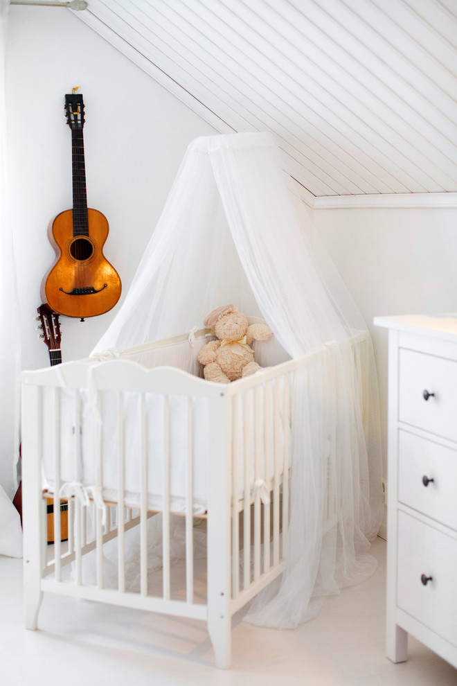 Immagine di una piccola cameretta per neonati neutra scandinava con pareti bianche e pavimento bianco