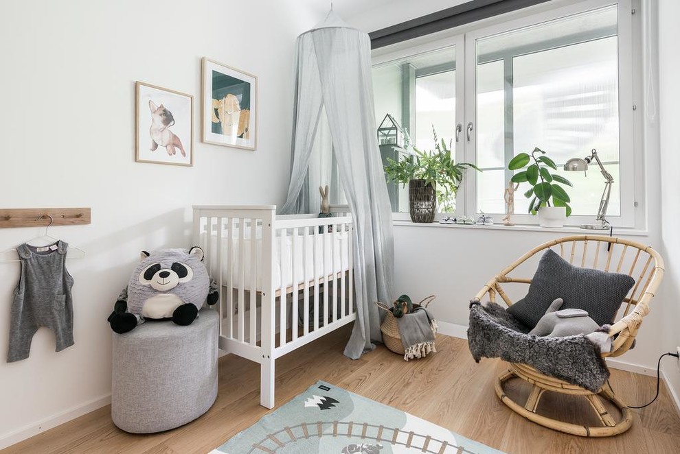 Diseño de habitación de bebé neutra escandinava con paredes blancas y suelo de madera clara