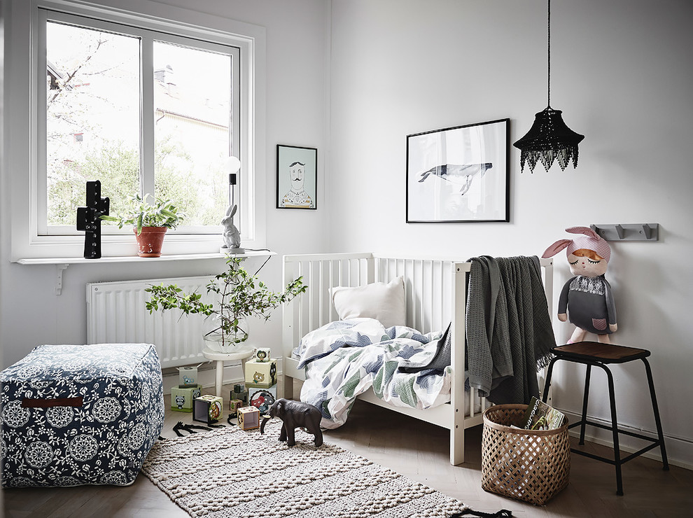 На фото: нейтральная комната для малыша в скандинавском стиле с белыми стенами, светлым паркетным полом и бежевым полом