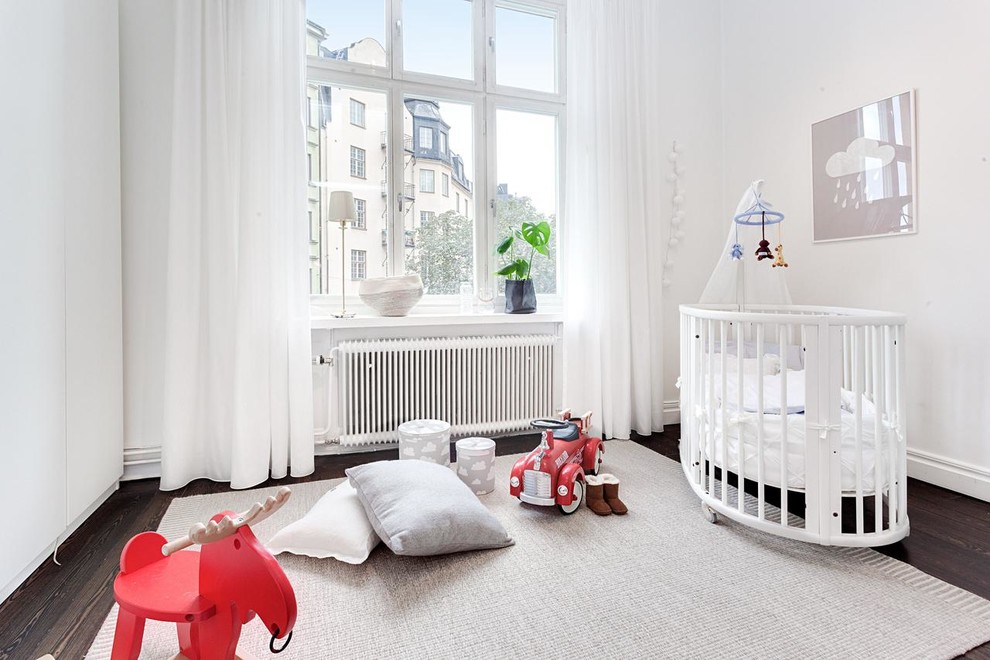 Immagine di una grande cameretta per neonati neutra scandinava con pareti bianche e parquet scuro