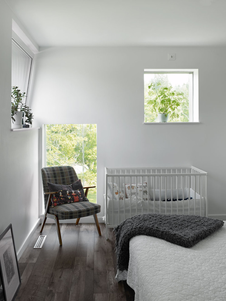 Cette photo montre une chambre de bébé neutre tendance de taille moyenne avec un mur blanc, parquet foncé et un sol marron.