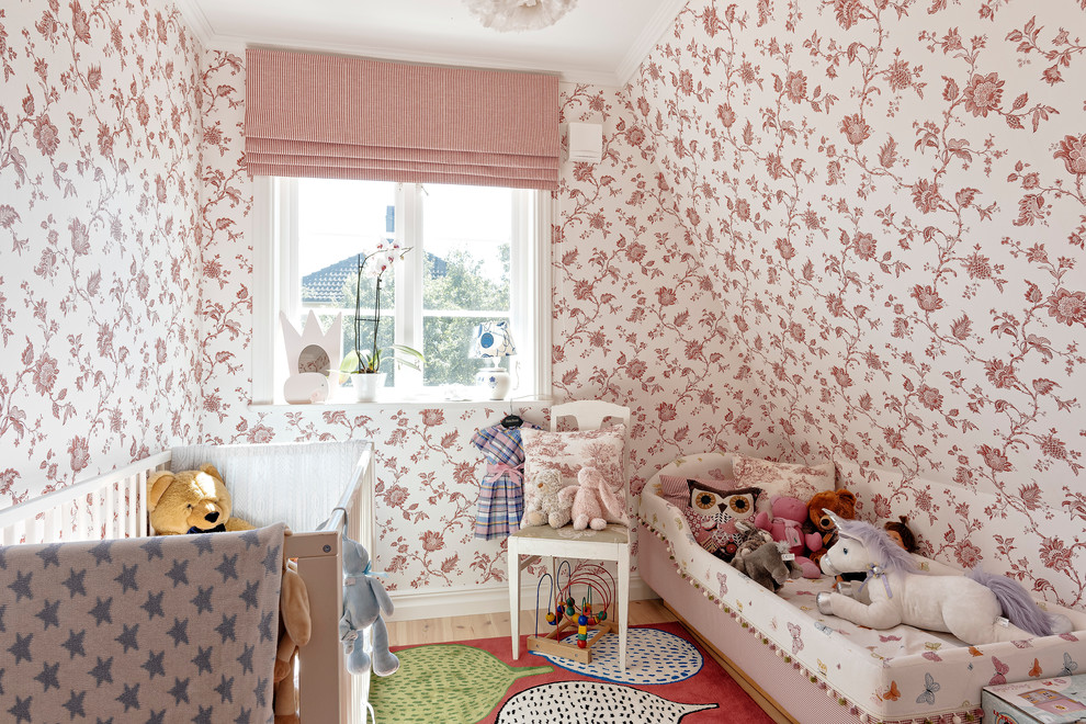 Immagine di una cameretta per neonati neutra scandinava di medie dimensioni con pareti multicolore e parquet chiaro