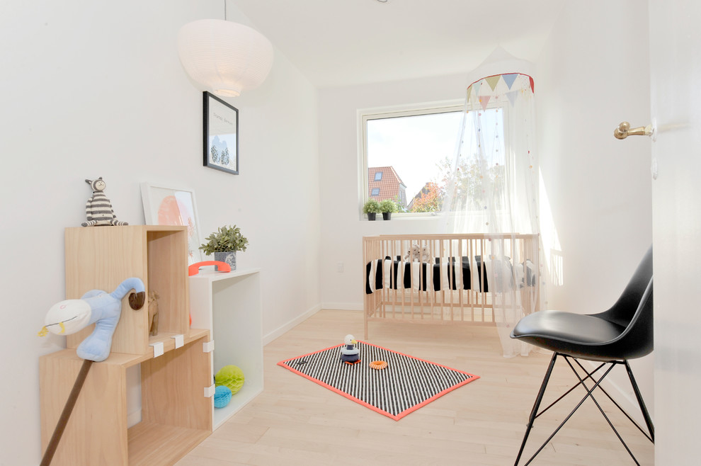 На фото: нейтральная комната для малыша среднего размера в скандинавском стиле с белыми стенами, светлым паркетным полом и бежевым полом с