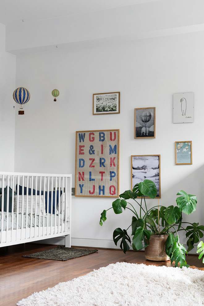 Nursery - scandinavian gender-neutral medium tone wood floor and brown floor nursery idea in Aarhus with white walls