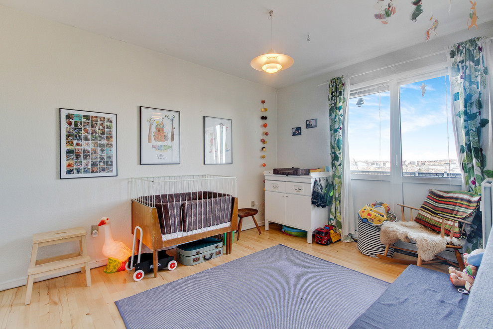 Photo of a large contemporary nursery for boys in Aalborg with white walls and light hardwood flooring.