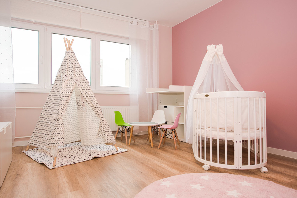 Mittelgroßes Modernes Babyzimmer mit rosa Wandfarbe, braunem Holzboden und braunem Boden in Berlin