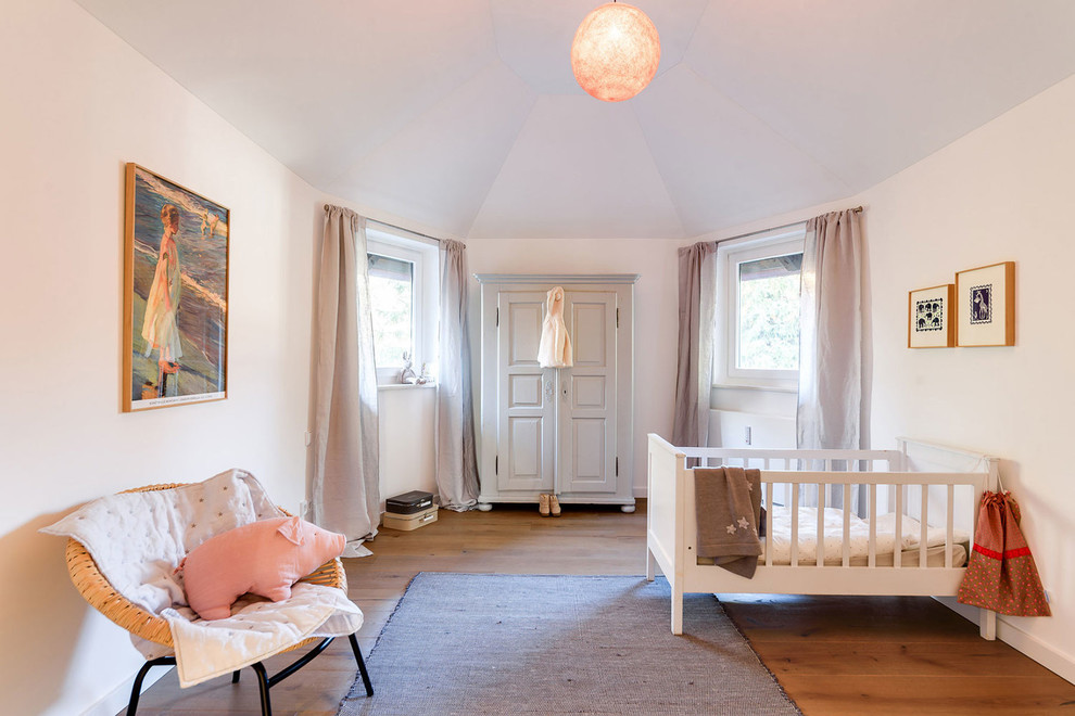 Cette image montre une chambre de bébé neutre nordique de taille moyenne avec un mur blanc, un sol en bois brun et un sol marron.