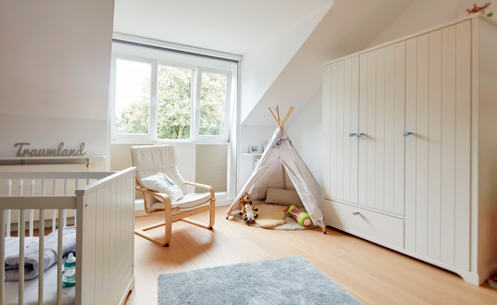 Mittelgroßes Skandinavisches Babyzimmer mit weißer Wandfarbe, hellem Holzboden und beigem Boden in Bremen