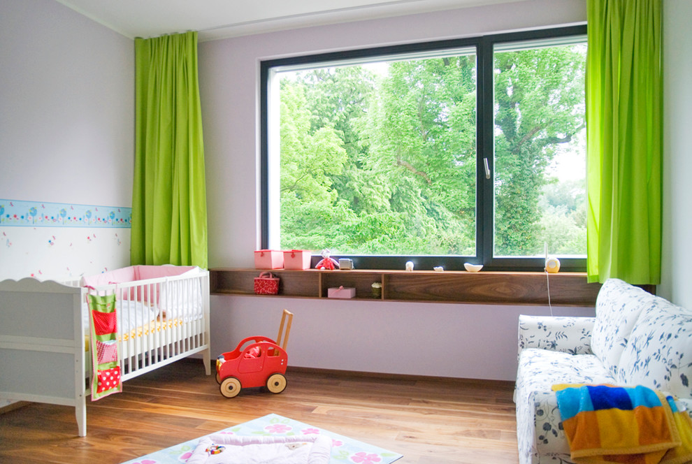 Ejemplo de habitación de bebé neutra actual de tamaño medio con paredes blancas y suelo de madera oscura