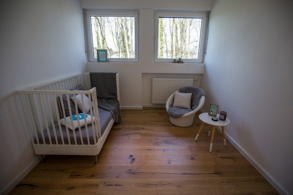 Kleines, Neutrales Modernes Babyzimmer mit weißer Wandfarbe, braunem Holzboden und braunem Boden in Sonstige