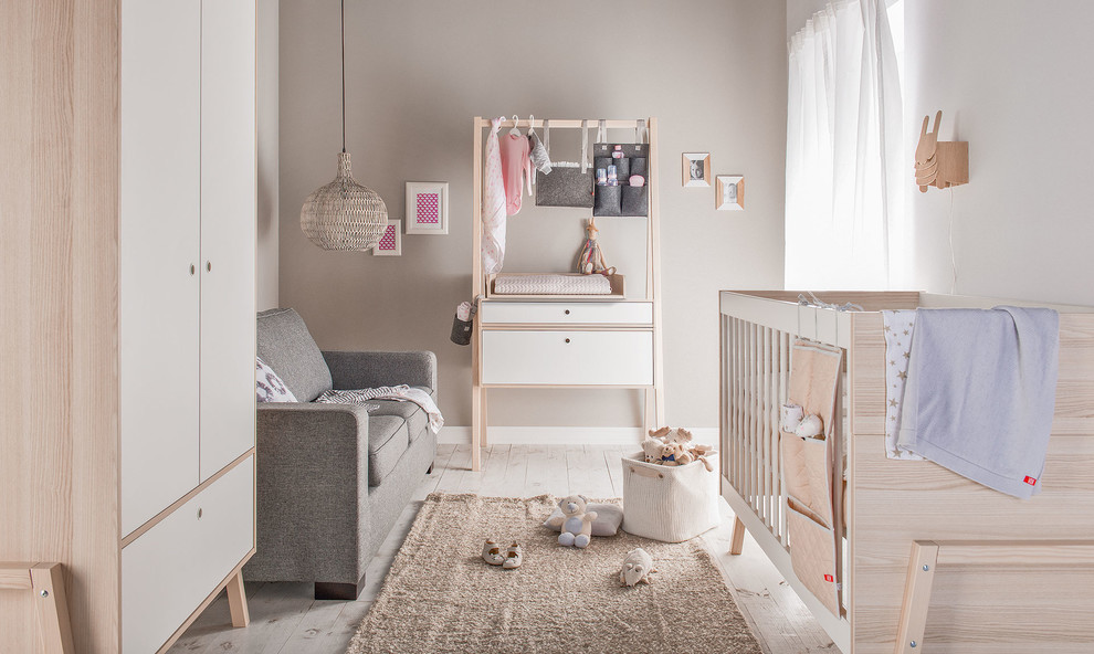 Design ideas for a small scandi nursery for girls in Dresden with brown walls, light hardwood flooring, beige floors and feature lighting.