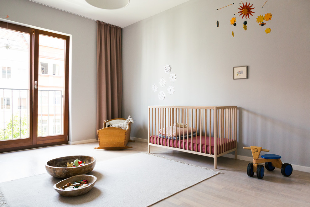 Aménagement d'une chambre de bébé neutre scandinave de taille moyenne avec un mur gris, parquet clair et un sol beige.