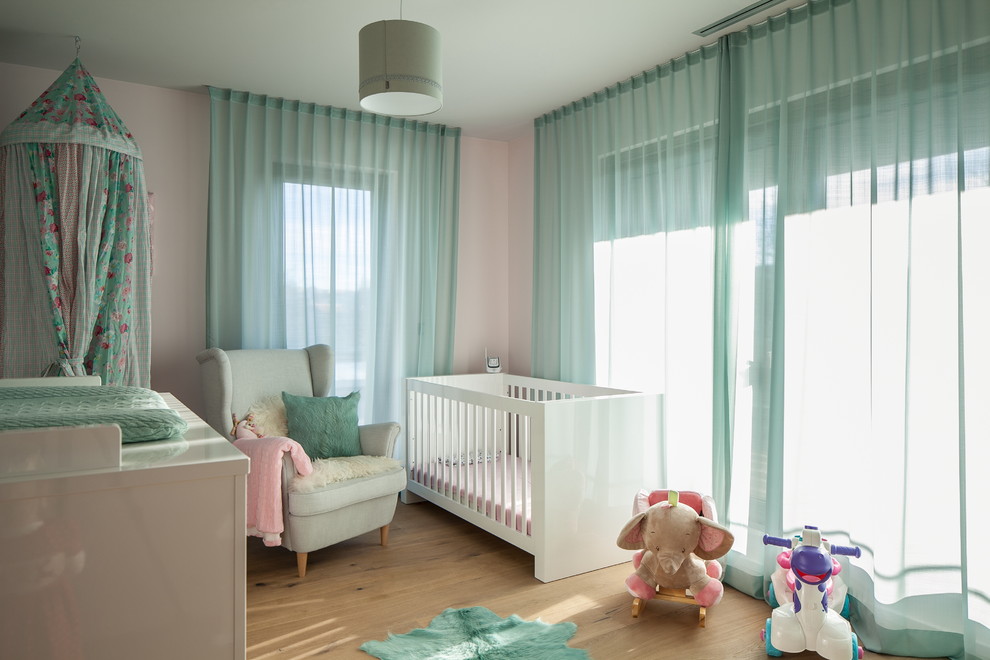 Foto de habitación de bebé niña tradicional de tamaño medio con paredes rosas, suelo de madera clara y suelo marrón