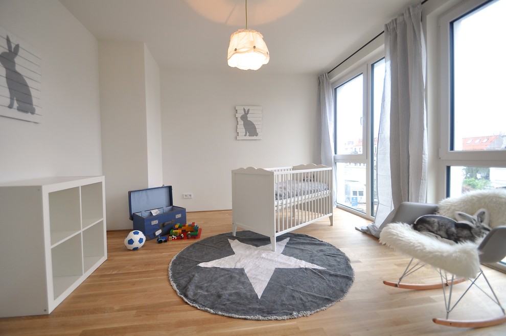 Diseño de habitación de bebé niño escandinava grande con paredes blancas y suelo de madera en tonos medios