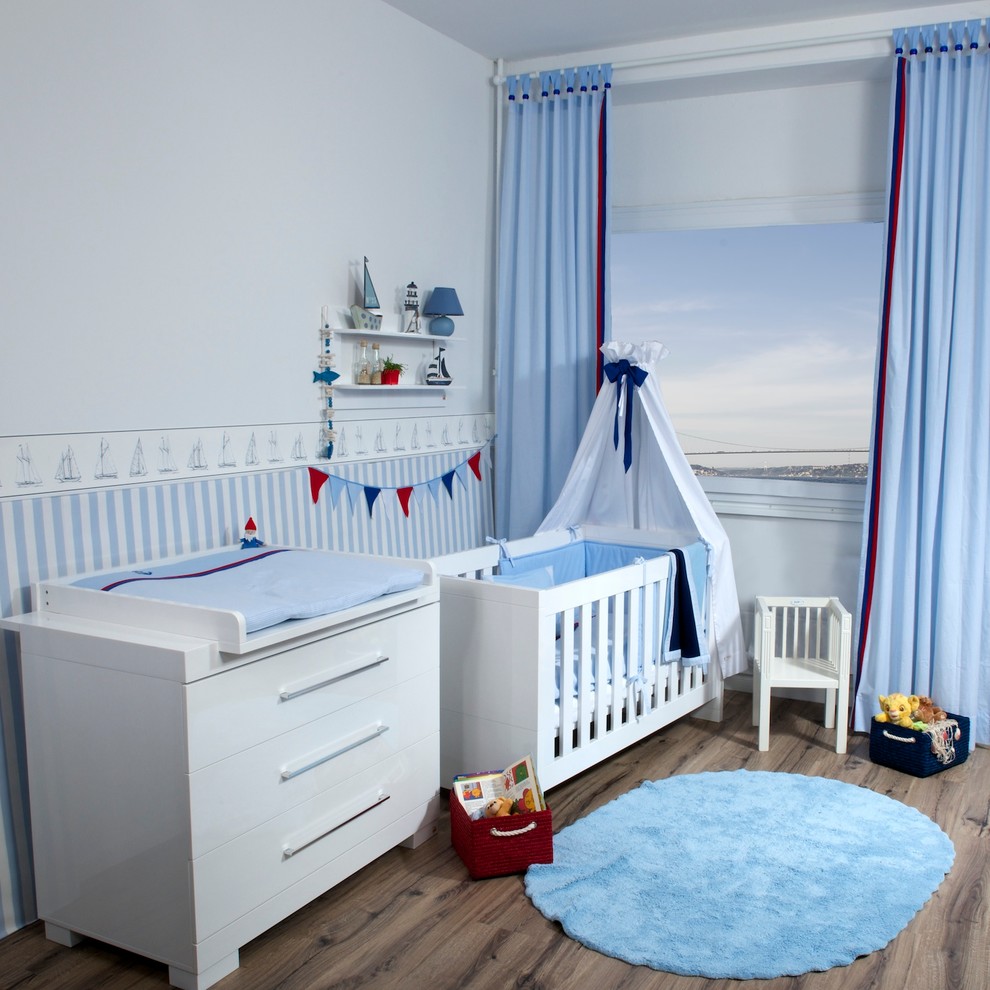 Nautical nursery for boys in Munich with blue walls, dark hardwood flooring and brown floors.