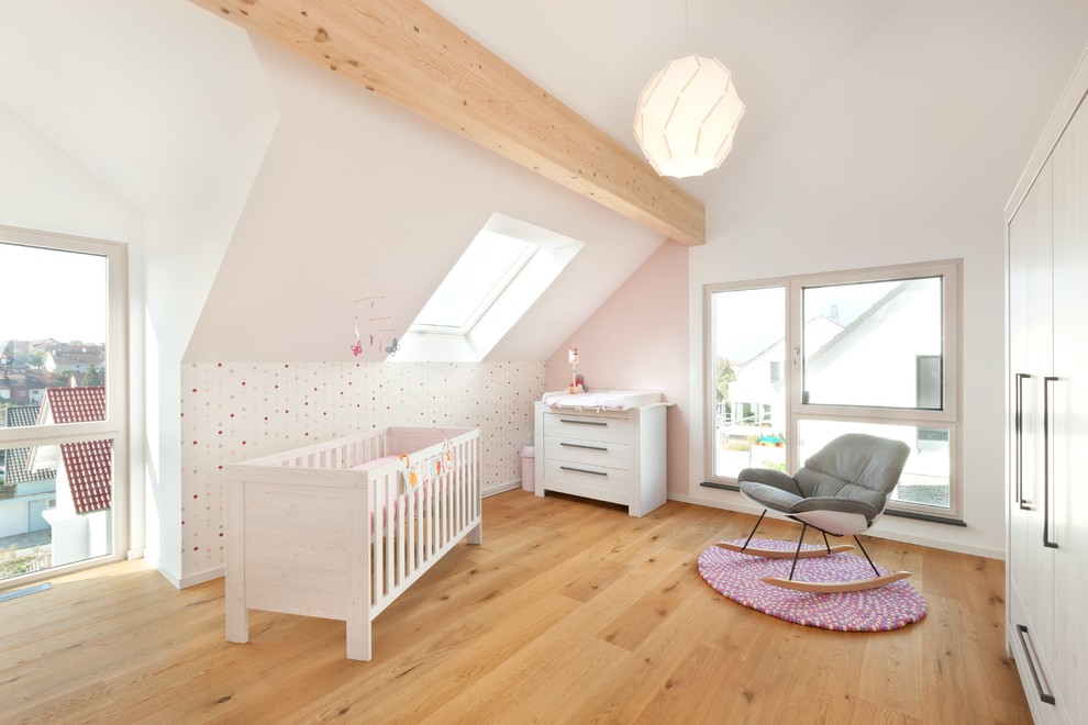 Immagine di una grande cameretta per neonata design con pareti bianche, parquet chiaro e pavimento marrone