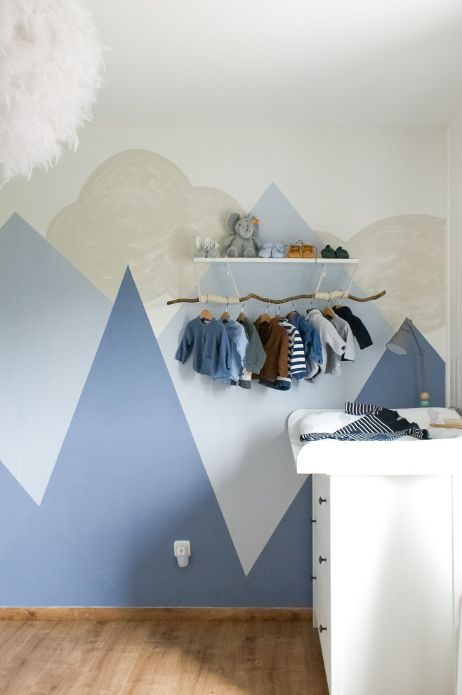 Idée de décoration pour une chambre de bébé garçon champêtre de taille moyenne avec un mur bleu, sol en stratifié et un sol marron.