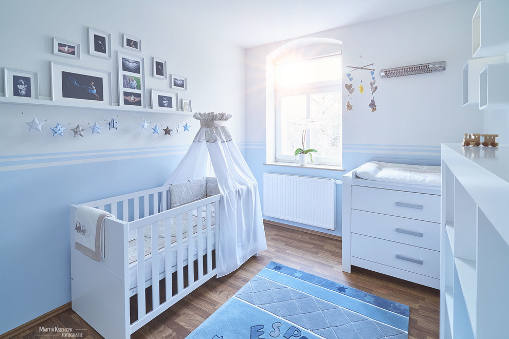 Foto de habitación de bebé neutra actual de tamaño medio con paredes blancas y suelo de madera oscura
