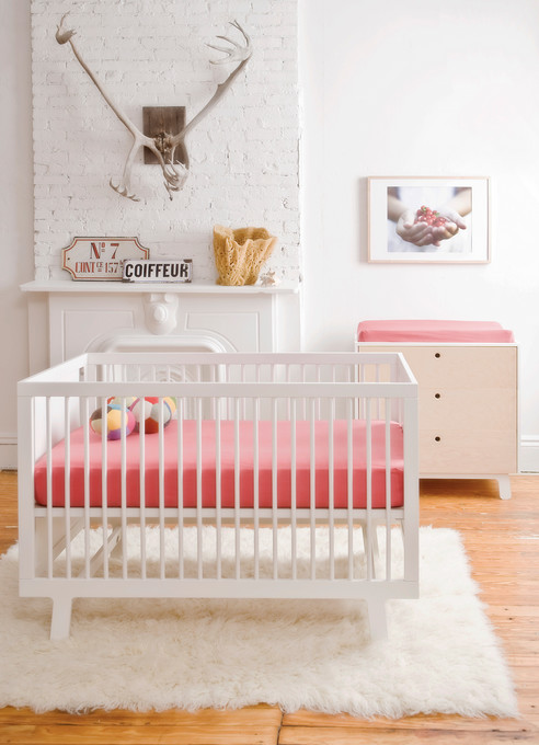 Idée de décoration pour une chambre de bébé fille design avec un mur blanc et parquet peint.